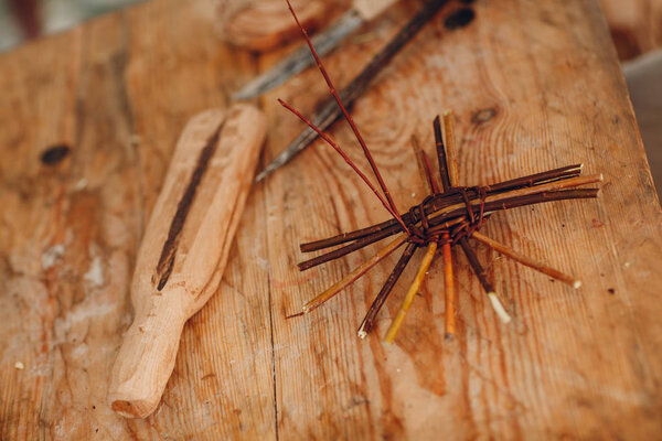 Мастер плетёт корзину из веток.
