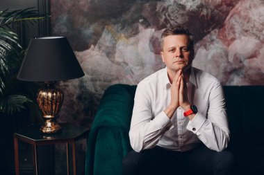 Yeşil kanepe oturan beyaz gömlekli bir işadamının portresi. İş ve başarı kavramı.