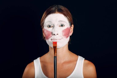 Makyaj yapan, yüzünü fırça ve makyajla boyayan genç bir kadın. Barışma konsepti nasıl yapılmaz.