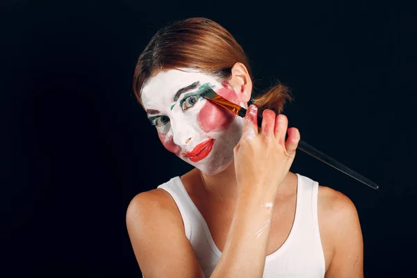 メイクアップを施した若い女性は 塗装ブラシやメイクアップペイントで顔をペイントします コンセプトを作らない方法 — ストック写真