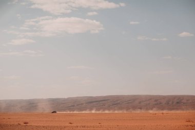 Jeep hızla çölde dumanlı yol alır.
