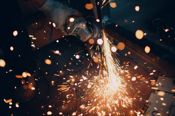 Craftsman sawing metal with disk grinder saw in workshop