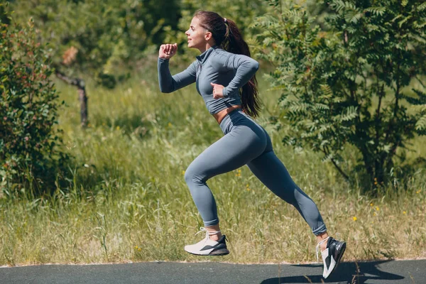 シティパークのランニングガール。若い女性は屋外ジョギングを実行します。サイドビュー. — ストック写真