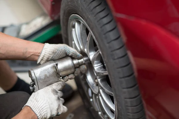 Reparación o cambio de neumáticos vehículo mecánico atornillar rueda del coche en la estación de servicio de reparación —  Fotos de Stock