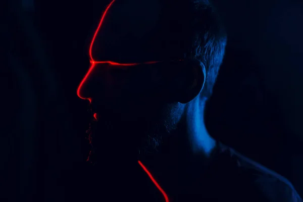 Hombre en oscuridad con la cara cruzada iluminada por láser rojo en el contorno. Escaneo facial — Foto de Stock