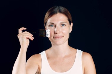 Makyaj yapan genç bir kadın, fırçayla yüzünü boyayan..