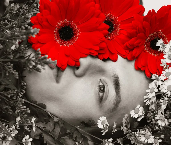 Junger Mann Modell mit Blumen. Schönheitsporträt. Einfarbig schwarz und rot — Stockfoto