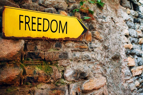 Flèche jaune sur un vieux mur de briques de pierre. Pointeur de direction avec inscription Freedom — Photo