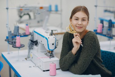 Genç, güzel terzi fabrikadaki dikiş makinesine dikiş dikiyor.