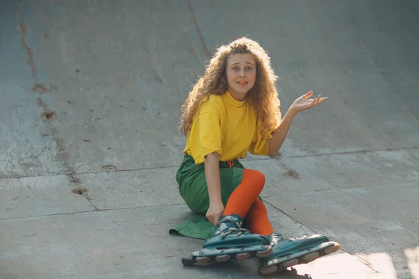 Chica joven en ropa verde y amarilla patinando sobre ruedas — Foto de Stock