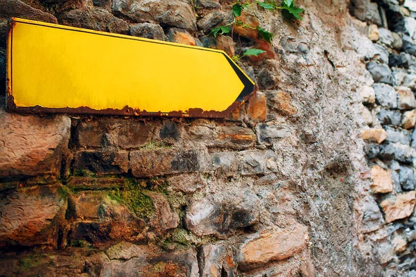 Tanda panah kuning di dinding batu tua. Penunjuk arah dengan ruang penyalinan kosong — Stok Foto