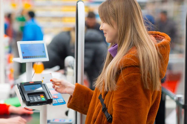 Jovem com cartão de crédito paga compras no balcão de check-out da loja . — Fotografia de Stock