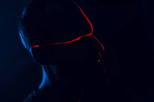 Hombre en la oscuridad con la cara iluminada por el escaneo láser rojo en el contorno — Foto de Stock