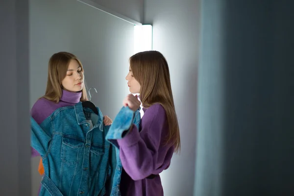 Wanita muda mencoba pakaian di ruang ganti dengan cermin di toko — Stok Foto