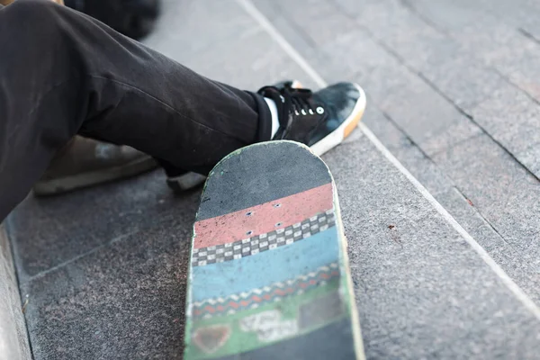 Mladý chlapec bruslař sedí s skateboard ve městě — Stock fotografie