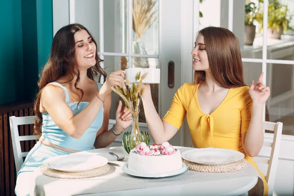 여자들은 집에 앉아서 흰색 생일 케이크와 차 한 잔과 함께 웃으며 행복 한 친구들 이다 — 스톡 사진