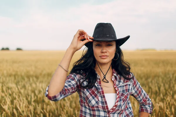 Donna contadina americana con cappello da cowboy, camicia a quadri e jeans al campo di grano — Foto Stock