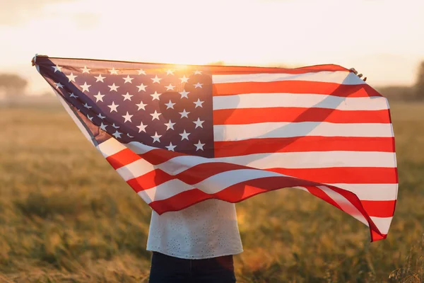 Silueta de mujer en el campo agrícola más allá de la bandera americana al atardecer — Foto de Stock