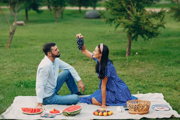 Jovem mulher adulta e homem casal piquenique com uva no prado de grama verde no parque — Fotografia de Stock
