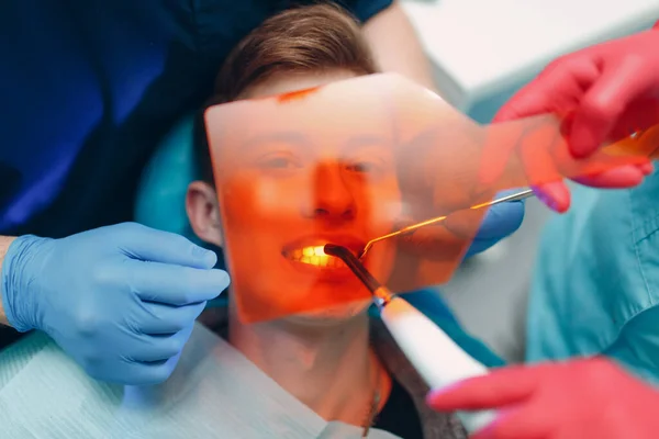 La dentisterie. Dentiste et patient. Joint de polymérisation léger. Lampe dentaire UV et verre protecteur orange. — Photo