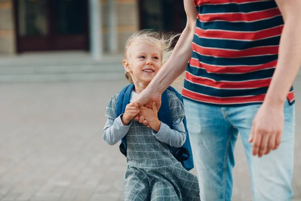 Achteraanzicht van vader die terugloopt naar school met zijn dochter die rugzak draagt — Stockfoto