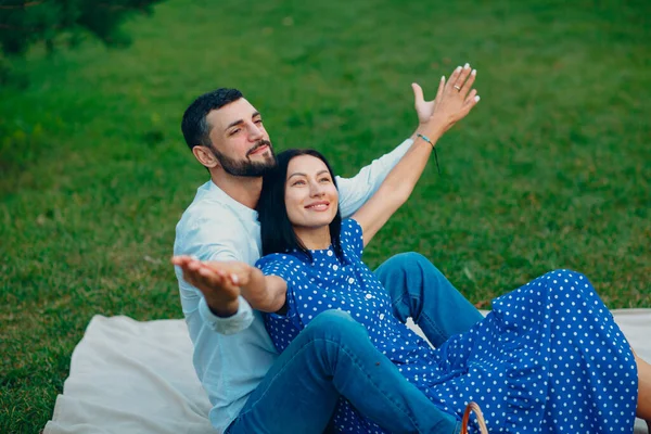 Mujer adulta joven y hombre pareja picnic en prado de hierba verde en el parque con los brazos abiertos — Foto de Stock