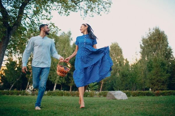 Casal feliz com frutas na cesta de piquenique Correndo no parque. — Fotografia de Stock