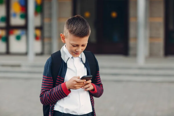 Школьник подросток с мобильным телефоном, стоящим в школе на заднем плане — стоковое фото