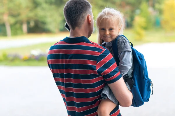 Visão traseira do pai voltando para a escola com sua filha carregando mochila — Fotografia de Stock