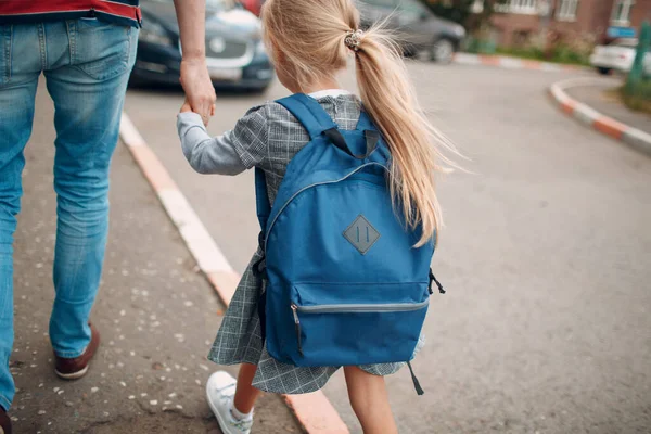 Achteraanzicht van vader die terugloopt naar school met zijn dochter die rugzak draagt — Stockfoto