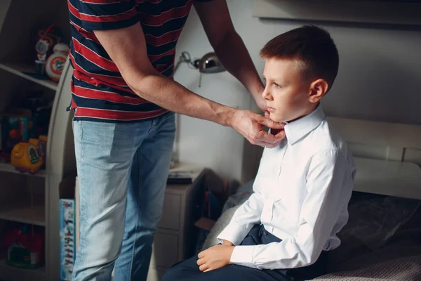 Vader helpt zoon knopen zijn shirt en dressing uniform voorbereiding terug naar school. — Stockfoto