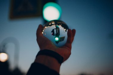 Gece şehir caddesinde trafik ışıkları olan cam küreyi tutan el.