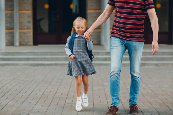 Achteraanzicht van vader die terugloopt naar school met zijn dochter die rugzak draagt — Stockfoto