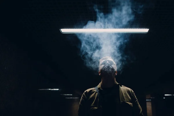 Portré fiatal fehér férfi dohányzik e-cigaretta a sötétben a vonal fény — Stock Fotó