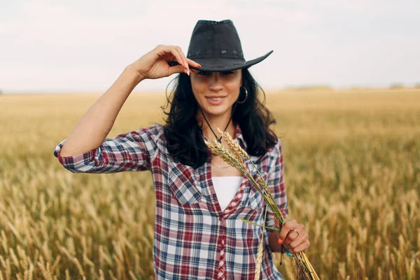 Donna contadina americana con cappello da cowboy, camicia a quadri e jeans al campo di grano — Foto Stock