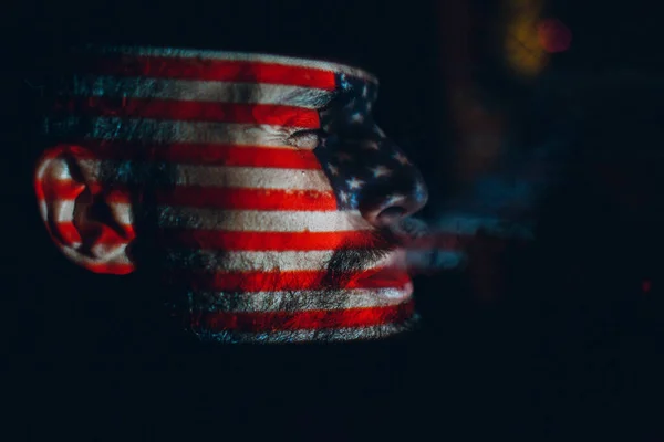 Взрослый мужчина с флагом США на лице в темноте. — стоковое фото