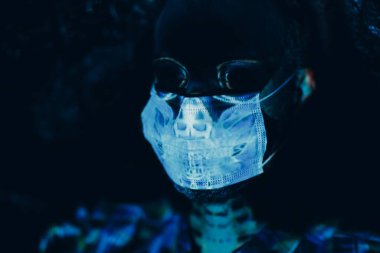 Cadılar Bayramı 'nda tıbbi maske takmış yetişkin bir adamın kafatası portresi.