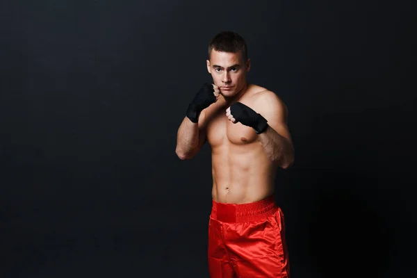 Deportista muay thai hombre boxeador postura en rojo troncos en negro fondo —  Fotos de Stock