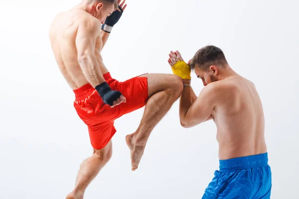 İki erkek boksör muay thai ile dövüşüyor ve beyaz arka planda dizlerini tekmeliyor. Hareket bulanıklığı. — Stok fotoğraf