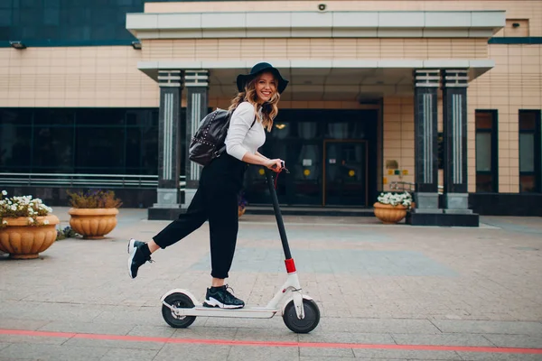 Ung kvinna med elektrisk skoter på staden — Stockfoto