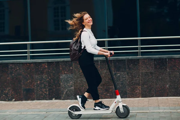 Ung kvinna med elektrisk skoter på staden — Stockfoto