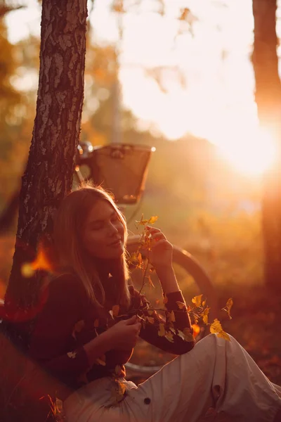 Happy active young woman sitting with vintage bicycle in autumn park at sunset — Stock Photo, Image