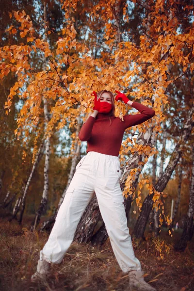 Wanita muda yang aktif dalam sarung tangan merah dan masker wajah di taman musim gugur — Stok Foto