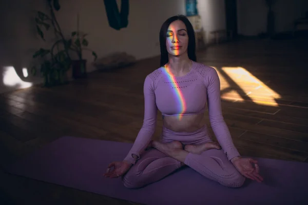 Vrouw die meditatie en yoga beoefent met regenboog licht op haar lichaam en gezicht — Stockfoto