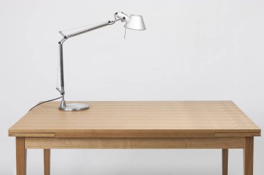 Ahşap masada gümüş lamba var..