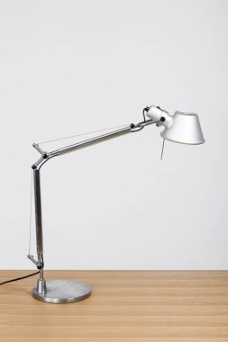 Ahşap masada gümüş lamba var..