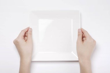 Kadın beyaz arka planda izole edilmiş beyaz bir çanağı (kase) tutuyor.