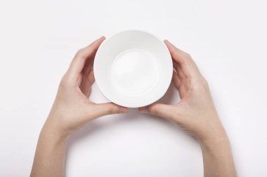 Kadın beyaz arka planda izole edilmiş beyaz bir çanağı (kase) tutuyor.