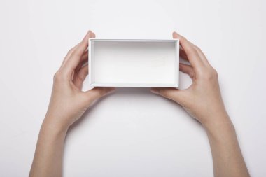 Beyaz masada beyaz bir kutu tutan bir kadın.