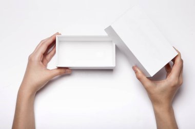 Beyaz masada beyaz bir kutu tutan bir kadın.